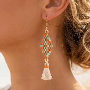 Close-up detail of bohemian handmade seed bead tassel earrings, colorful geometric diamond shape.