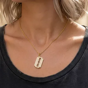 Gros plan détaillé du pendentif rasoir en zircon scintillant sur une chaîne dorée élégante.