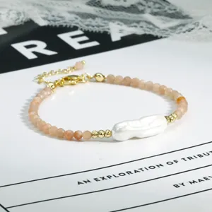 Detailopname van de onregelmatige barokke parel en roze kristallen armband met gouden accenten.