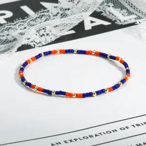 Nahaufnahme des bunten Perlenarmbands mit blauen und orangen Rocailles sowie goldenen Details.