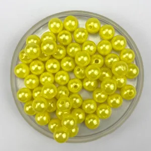 Close-up detail of glossy yellow ABS pearl beads in a clear tray for DIY jewelry making crafts.