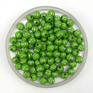Detail shot of green acrylic pumpkin beads with silver stripes for DIY jewelry making.