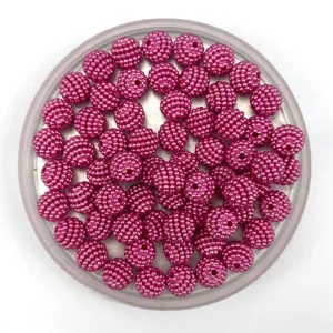 Gros plan de perles DIY texturées rose vif, parfaites pour les bijoux faits main et les loisirs.