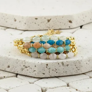 Close-up van een meerstrengs gefacetteerde halfedelstenen kralenarmband met gouden accenten.