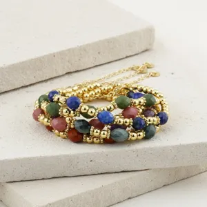 Detailopname van de meerstrengs kralenarmband met kleurrijke halfedelstenen en gouden kralen.