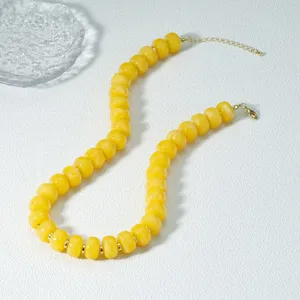 Primo piano dettagliato della collana di perle in acrilico giallo abaco con dettagli dorati.