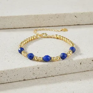 Detailopname van gouden kralenarmband met blauwe lapis lazuli halfedelstenen stenen