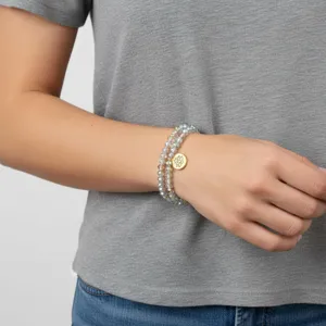 Primer plano detallado de una pulsera de cuentas de cristal multicapa con dije de loto.