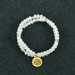 Primer plano de la pulsera de cuentas blancas de doble capa con colgante de flor de loto dorada.