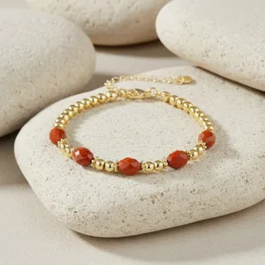Prachtig kralenarmband detail met gouden ballen en rode gefacetteerde edelstenen hier.
