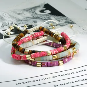 Gedetailleerde close-up van boheemse kleurrijke kralen gestapelde armbanden met gouden spacers.