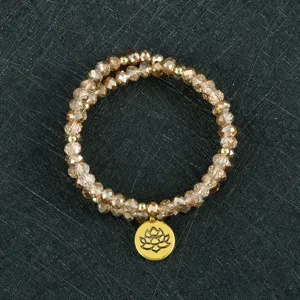 Vista detallada de una pulsera de cuentas multicapa con cuentas de cristal y un colgante de loto.