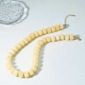 Primo piano dei dettagli della collana di perle in acrilico giallo con distanziatori.