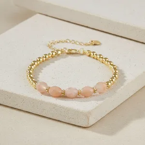 Gedetailleerd overzicht van een vintage kralenarmband met verguld metaal en roze edelstenen.