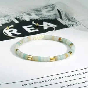 Close-up van boho kraal armband met kleurgeblokkeerde goudkleurige buizen en verstelbaar koord.