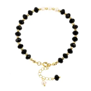 Gedetailleerd overzicht van een Boheemse zwarte gefacetteerde kralenarmband met witte parels.