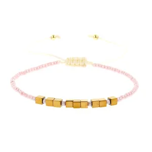 Handgemaakte kralenarmband met roze zaadkralen en gouden metalen kubusbedels
