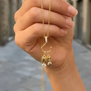 Vue de détail du magnifique collier pendentif hameçon et petits poissons en zircon doré.