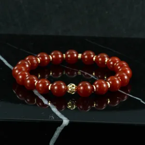 Primer plano detallado de la pulsera de cuentas rojas con separadores metalicos dorados y cuenta central.