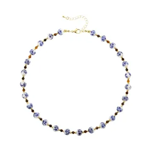 Close-up detail of blue and white porcelain ceramic beads necklace with golden metal clasp link.