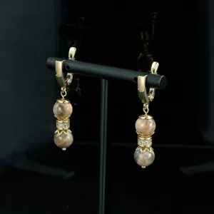 Elegantes pendientes de piedra natural con montura dorada y detalles de circonita brillante.