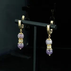 Detalle de primer plano pendientes colgantes vintage perlas moradas chapados en oro con separador.