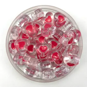Primo piano dettagliato di perline a cuore in acrilico trasparente con nucleo rosa per gioielli.