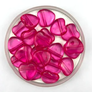 Close-up detail of translucent pink heart-shaped acrylic beads with horizontal hole for DIY crafts.
