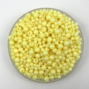 Detailed close-up view of macaron yellow acrylic plastic beads in a transparent tray for DIY.