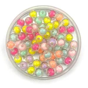 Gros plan détaillé de perles DIY transparentes et colorées à double couche dans une boîte.
