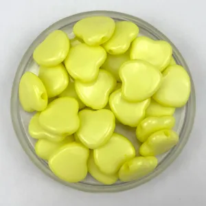 Close-up detail of yellow acrylic heart-shaped loose beads with horizontal holes for DIY jewelry.