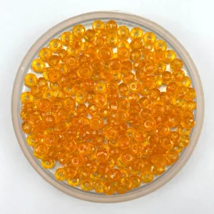 Close-up of vibrant orange faceted acrylic crystal rondelle beads in a round transparent tray.