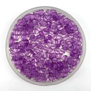 Detail view of purple transparent heart plastic beads in a round container, perfect for DIY jewelry.