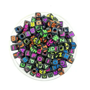 Close-up detail of black acrylic square alphabet beads with colorful letters for DIY jewelry.