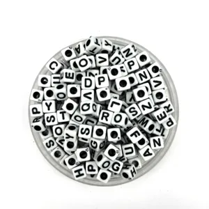 Close-up view of white square acrylic alphabet letter beads inside a clear storage container.
