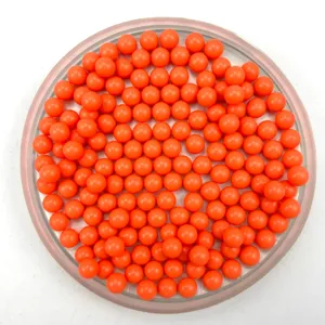 Closeup detail of vibrant orange solid round plastic beads displayed in tray for DIY crafts.