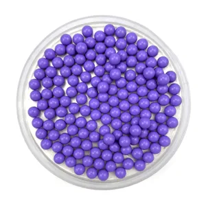 Close-up detail of solid purple round plastic acrylic beads and toy marbles in clear tray.