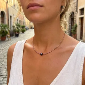 Close-up detail of a delicate beaded clavicle chain necklace featuring dainty purple stones.