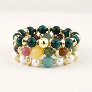 Close-up van meerlaagse kleurrijke edelsteen- en parelkralenarmband met gouden spacers.