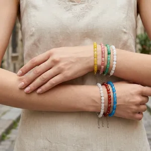 Detailopname van kleurrijke edelsteen kralenarmbanden gedragen aan de arm, mode.