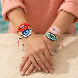Primo piano di bracciali di perline Miyuki artigianali con occhio malvagio e labbra rosse.