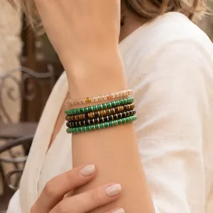 Stacked beaded bracelets worn on wrist detail view, featuring natural stones and metal accents.