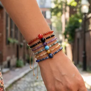 Close-up detail shot of handmade colorful beaded layered bracelets featuring unique stone beads.