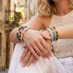 Detailopname van meerlaagse Edelstenen kralenarmbanden met kleurrijke stenen en gouden kettingen.