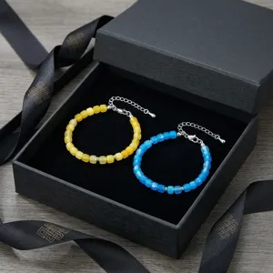 Detailopname van kleurrijke gefacetteerde kralenarmbanden in een zwarte geschenkdoos.