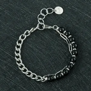 Detailopname van de tweelaagse zilveren kettingarmband met zwarte kralen en liefdeslabel.