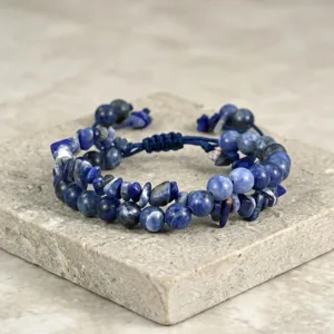 Detailopname van edelsteen kralenarmband met geweven koord en blauwe steentjes.