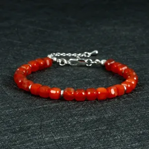 Detailopname van gefacetteerde rode karneool edelsteen kralenarmband met zilveren tussenkraal.