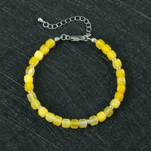 Gedetailleerd overzicht van gele gefacetteerde natuurstenen kralenarmband met zilveren sluiting.