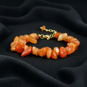 Gedetailleerde close-up van onregelmatige oranje edelsteenarmband met metalen sluiting.
